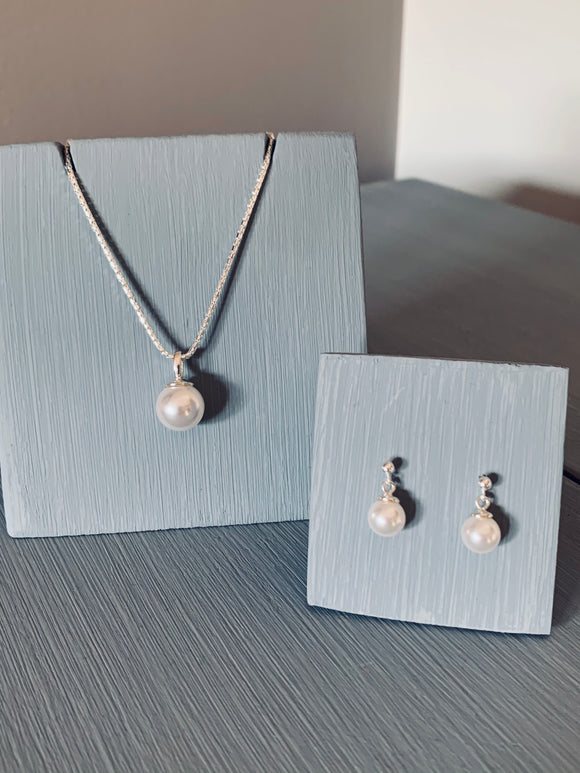  classic Pearl jewellery set. Each piece features lustrous 10mm pearl gracefully adorning a sterling silver 18-inch chain necklace, paired with delicate drop earrings boasting 6mm pearls. 