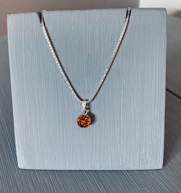 Set on a 925 Sterling Silver Chain is a necklace set with a Topaz Swarovski Crystal.